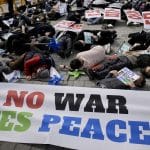 Protesters lie on the street in a performance of expressing their requirement about the peace and war crisis during a rally to oppose the planned the joint military exercises between the U.S. and South Korea, in Seoul, South Korea, Saturday, March 11, 2023. The South Korean and U.S. militaries will conduct computer-simulated command post training March 13-23 and will resume their largest springtime field exercises, which were last held in 2018. A part of letters read "Stop the war exercise." (AP Photo/Lee Jin-man)