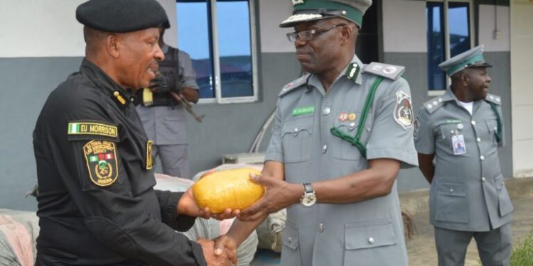 Alt="From L-R the Commander Marine, of the National Drug Law Enforcement Agency NDLEA, Mr Emmanuel Udoh and the Customs Area Controller, Western Marine command, Comptroller Paul Bamisaiye while handing over 18 sacks of cannabis sativa weighing 730kg to NDLEA in Lagos"